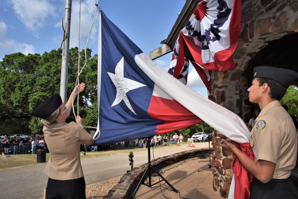 Bastrop Naval ROTC cadets Maddy Pickering (left) and Conner Shaw raise the Texas flag at the Memorial Day ceremony Monday at Fairview Cemetery.