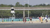 Guests walk from q parking lot to the entrance of the Magic Kingdom during the reopening at Walt Disney World Saturday, July 11, 2020, in Lake Buena Vista, Fla. (AP Photo/John Raoux)