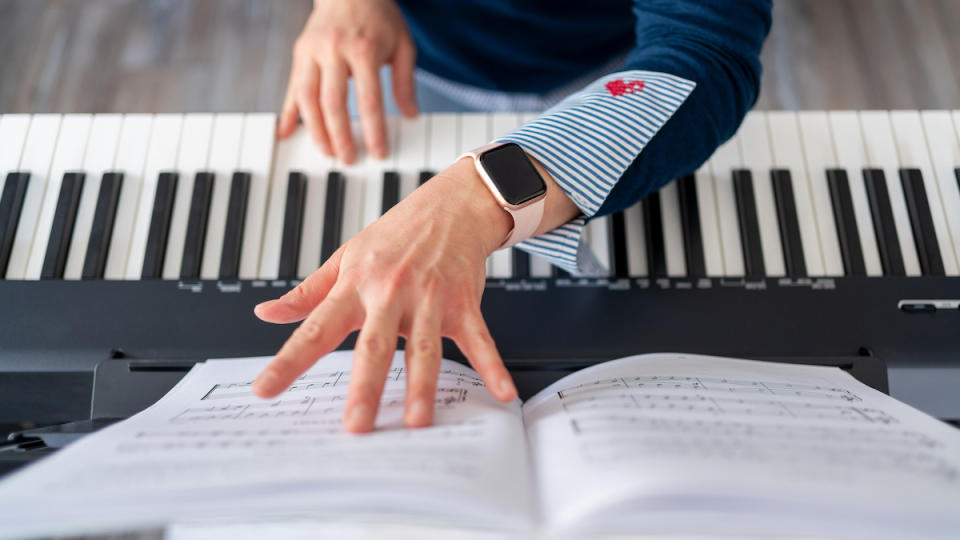 Overhead image of piano keys with hands turning a page of notation