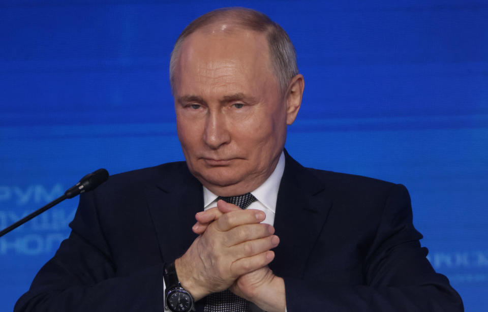 Russian President Vladimir Putin clasps his hands at an event in Moscow.