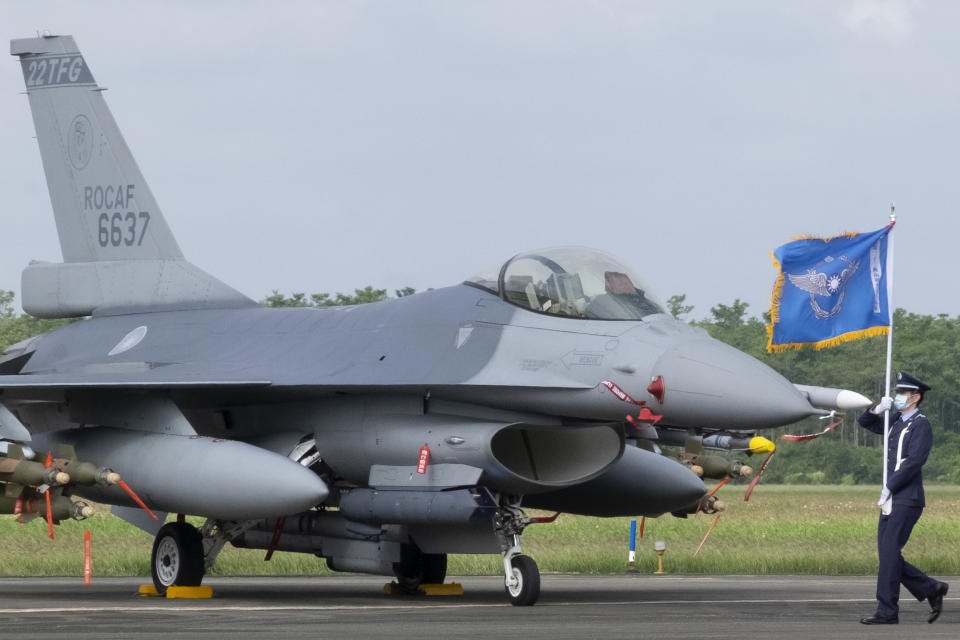 A Taiwanese Air Force flag bearer passes by one of the newly commissioned upgraded F-16V fighter jets at Air Force base in Chiayi in southwestern Taiwan Thursday, Nov. 18, 2021. Taiwan has deployed the most advanced version of the F-16 fighter jet in its Air Force, as the island steps up its defense capabilities in the face of continuing threats from China. (AP Photo/Johnson Lai)