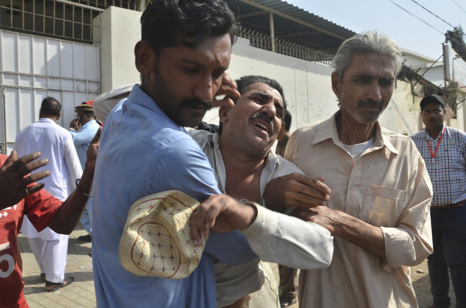 People comfort a family member of a police officer killed during a shootout at the Chinese Consulate in Karachi, Pakistan, Friday, Nov. 23, 2018. Armed separatists stormed the Chinese Consulate in Pakistan's southern port city of Karachi on Friday, triggering an intense hour-long shootout during which two police officers and all three assailants were killed, Pakistani officials said. (AP Photo/Shakil Adil)