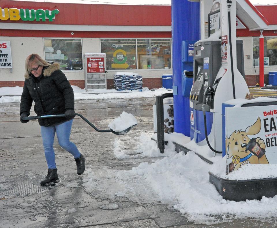 Kerrie Burkepile of South Market Street Bell Store in Wooster shovels snow around the pumps for her customers on Monday morning.