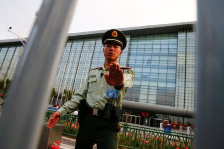 A paramilitary police officer prevents the photographer from taking pictures in front of the China National Convention Center, a venue of the upcoming Belt and Road Forum in Beijing, China, May 12, 2017. REUTERS/Thomas Peter