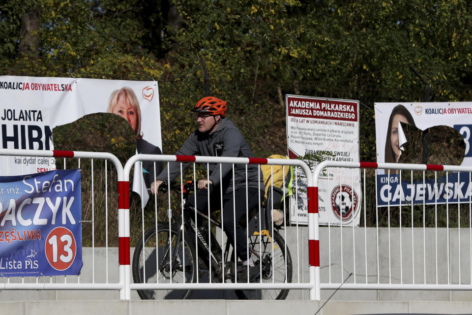 A cyclist rides past damaged electoral posters in Warsaw, Poland, Monday, Oct. 14, 2019. Nearly complete results in Poland's weekend election confirm that the conservative ruling party Law and Justice capitalized on its popular social spending policies and social conservatism to do better than when it swept to power four years ago. (AP Photo/Czarek Sokolowski)