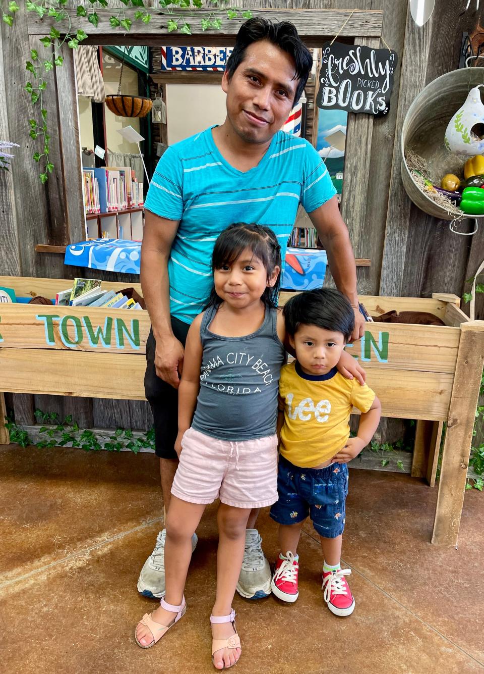 Remigio Solis and his kids, Maisey and Ezra Solis, spend time at Collinsville Public Library in Collinsville, Alabama, on July 18, 2023. The elder Solis, a long-time resident of the area, came to the United States speaking Chalchiteko, a dialect native to Huehuetenango. After learning Spanish, he tackled English by attending language classes at the Collinsville library.