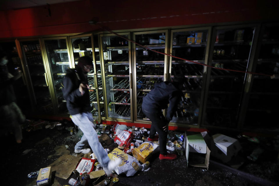 People take items from a liquor store Thursday, May 28, 2020, in Minneapolis. Protests over the death of George Floyd, a black man who died in police custody Monday, broke out in Minneapolis for a third straight night. (AP Photo/John Minchillo)