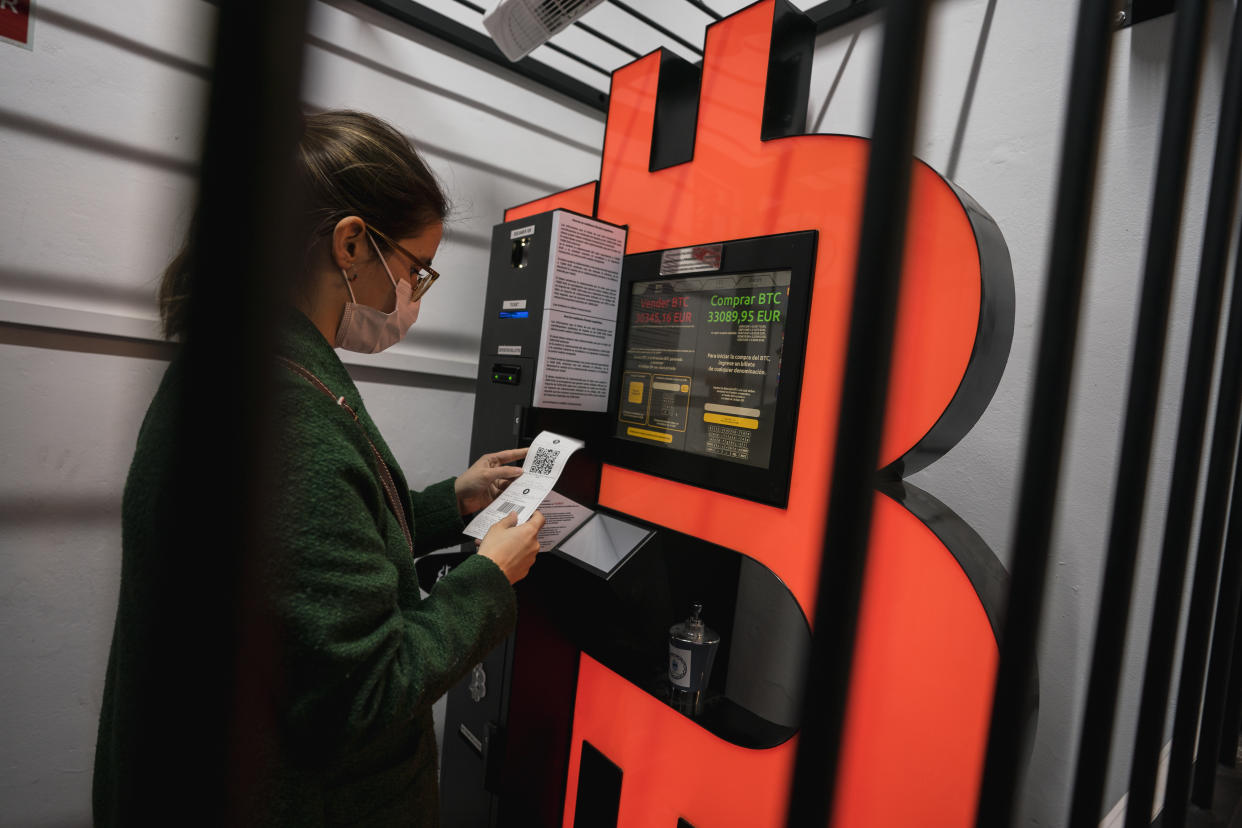 BARCELONA, SPAIN - JANUARY 29: A woman uses a Bitcoin ATM machine placed within a safety cage on January 29, 2021 in Barcelona, Spain. The European Union Agency for Law Enforcement Cooperation (Europol) and local law enforcement busted an allegedly fraudulent scam posing as a firm that specialized in cryptocurrency and foreign exchange investment training out of Andorra. (Photo by Cesc Maymo/Getty Images)