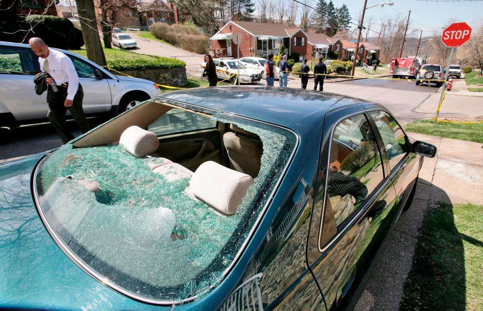 A Pittsburgh Police investigator, left rear, looks at a vehicle with its window shot out and a bullet hole in the roof, while investigating the neighborhood surrounding 1016 Fairfield street in the Stanton Heights section of Pittsburgh Sunday, April 5, 2009. 22-year-old Richard Poplawski, according to court papers, opened fire on Pittsburgh police officers responding to a 911 call from the gunman's mother, killing three officers and injuring one.