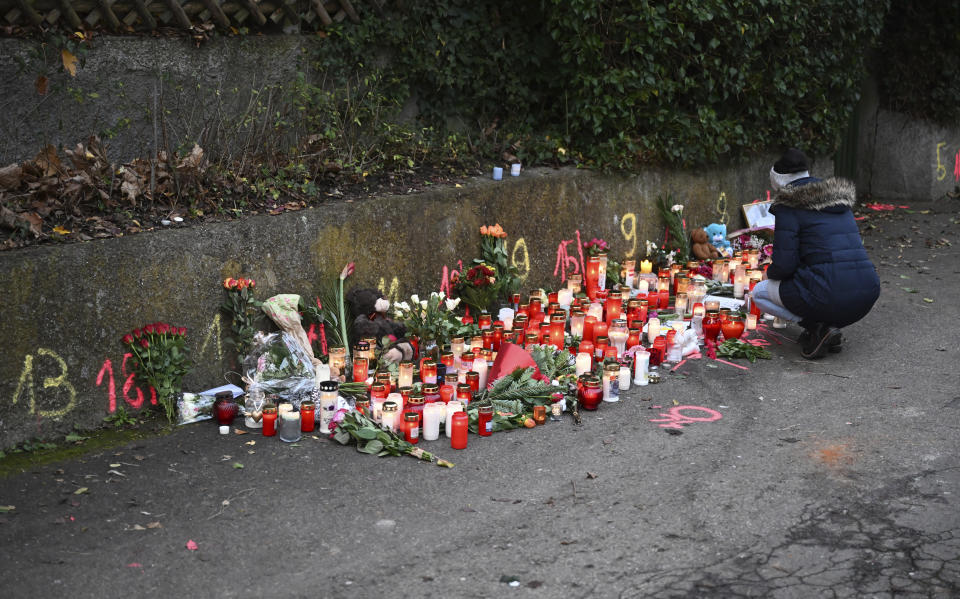 A woman lights a candle at the scene of a knife attack in Illerkirchberg, Tuesday, Dec.6, 2022. The day before, two girls were attacked by a man, a 14-year-old succumbed to her severe injuries. (Bernd Weissbrod/dpa via AP)