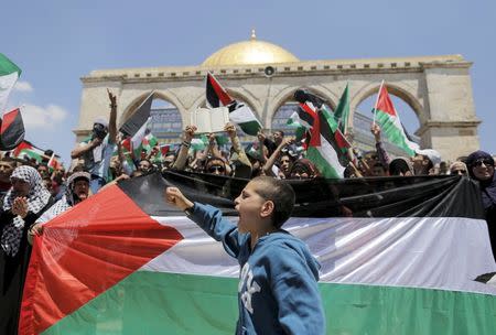 A Palestinian boy shouts slogans as others wave flags after Friday prayers during a protest to mark Nakba day near the Dome of the Rock on the compound known to Muslims as Noble Sanctuary and to Jews as Temple Mount, in Jerusalem's Old City in this May 15, 2015 file photo. REUTERS/Ammar Awad/Files