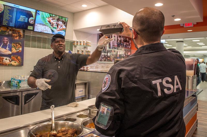 Un agente de la Administración de Seguridad del Transporte (TSA) recibe comida gratuita hoy de manos de Wilkinson Sejour (i), dueño de Chef Créole, único restaurante de comida haitiana en el Aeropuerto Internacional de Miami, Florida (Estados Unidos). EFE