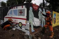 Workers paint a mural promoting coronavirus disease (COVID-19) awareness in Jakarta