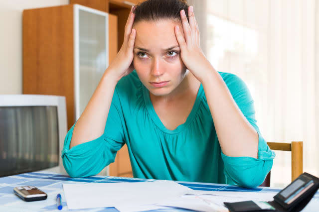 Young woman sitting depressed at the table because of financial problems