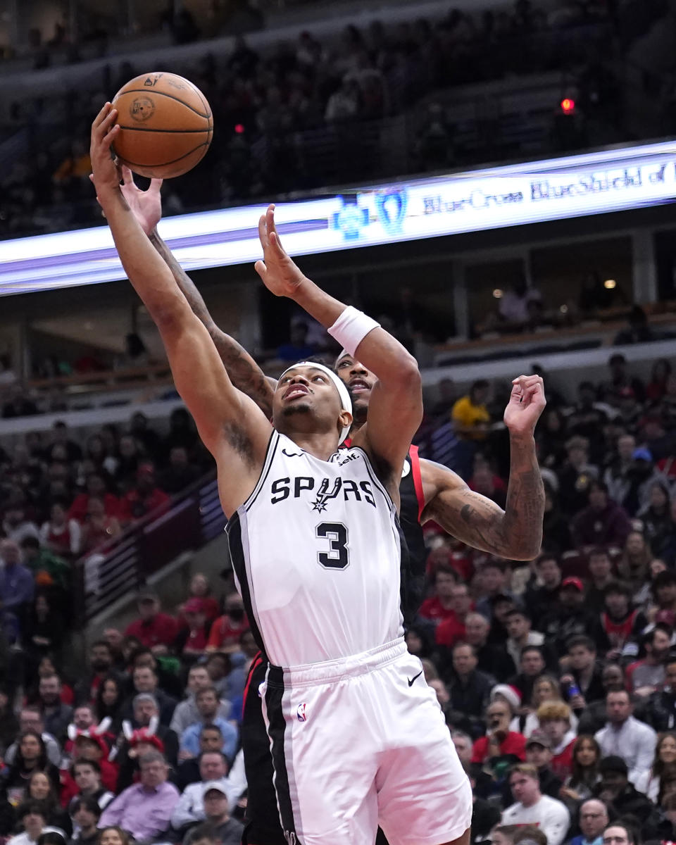 San Antonio Spurs' Keldon Johnson (3) drives to the basket past Chicago Bulls' DeMar DeRozan during the first half of an NBA basketball game Thursday, Dec. 21, 2023, in Chicago. (AP Photo/Charles Rex Arbogast)