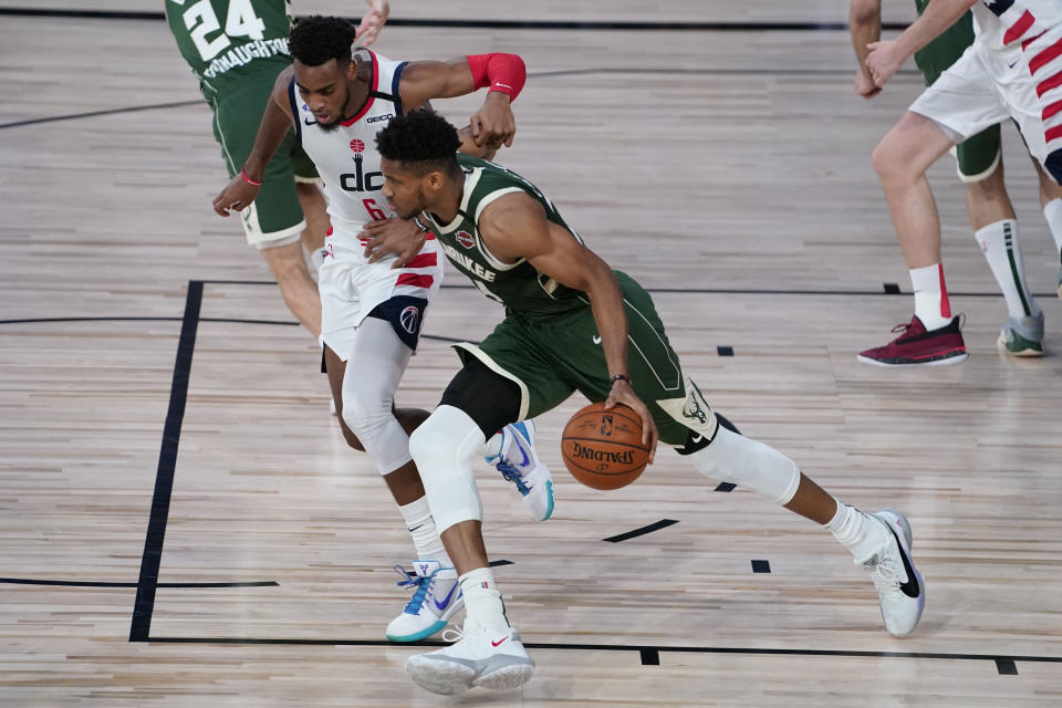 Milwaukee Bucks' Giannis Antetokounmpo powers past Washington Wizards' Troy Brown Jr., left, during the first half of an NBA basketball game, Tuesday, Aug. 11, 2020, in Lake Buena Vista, Fla. (AP Photo/Ashley Landis, Pool)