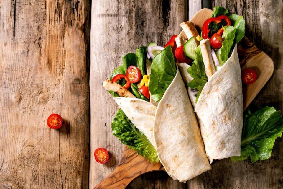 traditional mexican tortila wrap with pork meat and vegetables on wooden cutting board over brown wooden background top view flat lay copy space homemade fast food