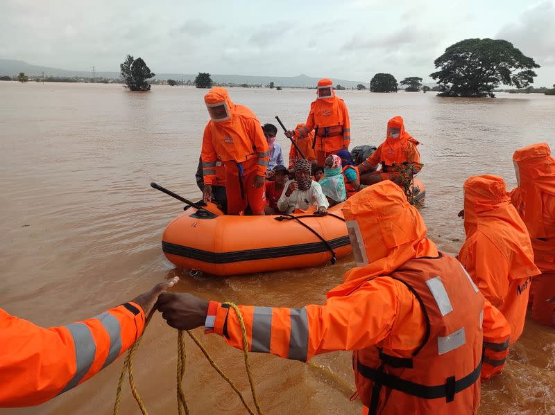 Members of NDRF evacuate people from a flooded area to safer places in Balinge village