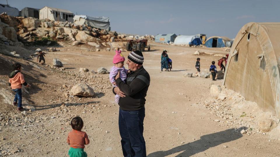 Ein Mann steht mit seinen Kindern in einem Flüchtlingslager in der Provinz Idlib.