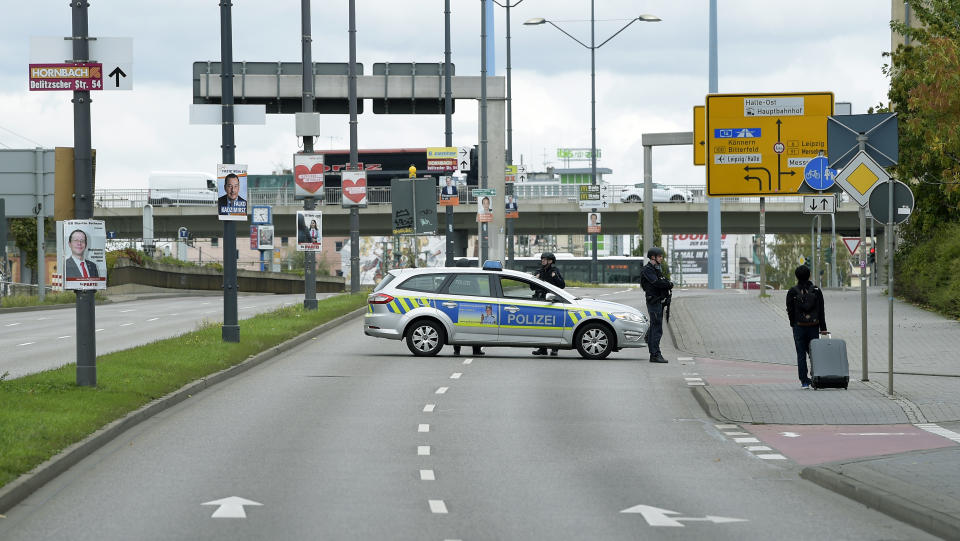 Police officers block a road in Halle, Germany, Wednesday, Oct. 9, 2019. One or more gunmen fired several shots on Wednesday in the German city of Halle. Police say a person has been arrested after a shooting that left two people dead. (AP Photo Jens Meyer)