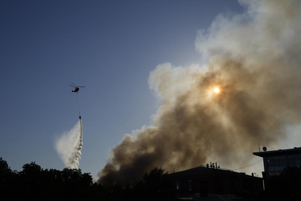 A Russian Emergency Situations Ministry helicopter dumps water on fire at a warehouse in Moscow, Russia, Saturday, June 19, 2021. A large fire broke out at a fireworks depot in the center of Moscow. The fire is raging at the area of 500 square meters, Russia emergency services said in the statement. (AP Photo/Pavel Golovkin)
