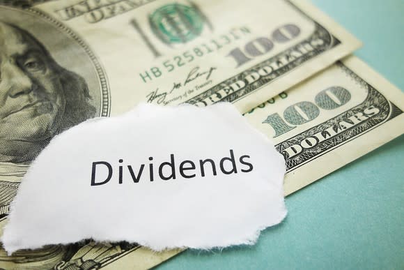 Piece of paper that says "dividends" sitting on top of $100 bills.