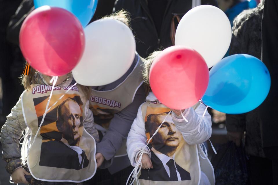 Dos niñas que visten camisetas con la imagen del presidente ruso Vladimir Putin sostienen globos con los colores de la bandera rusa en una manifestación a favor de los rusos en Crimea, en Moscú, Rusia, el lunes 10 de marzo de 2014. (Foto AP/Alexander Zemlianichenko)
