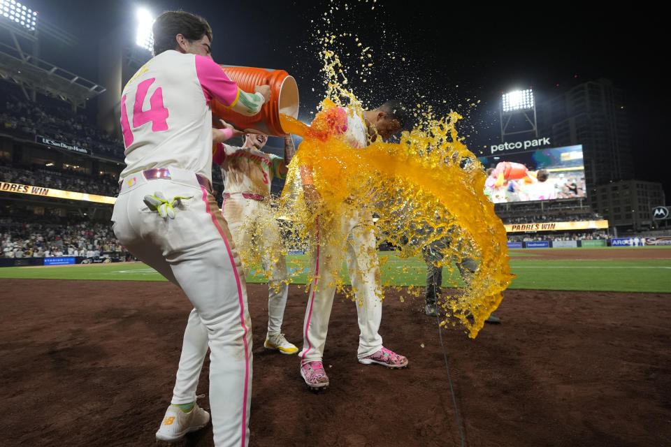 San Diego Padres' Manny Machado, right, is doused by teammates Tyler Wade, left, and Jackson Merrill after hitting a game-winning two-run home run during the ninth inning of a baseball game against the Arizona Diamondbacks, Friday, July 5, 2024, in San Diego. The Padres won, 10-8. (AP Photo/Gregory Bull)