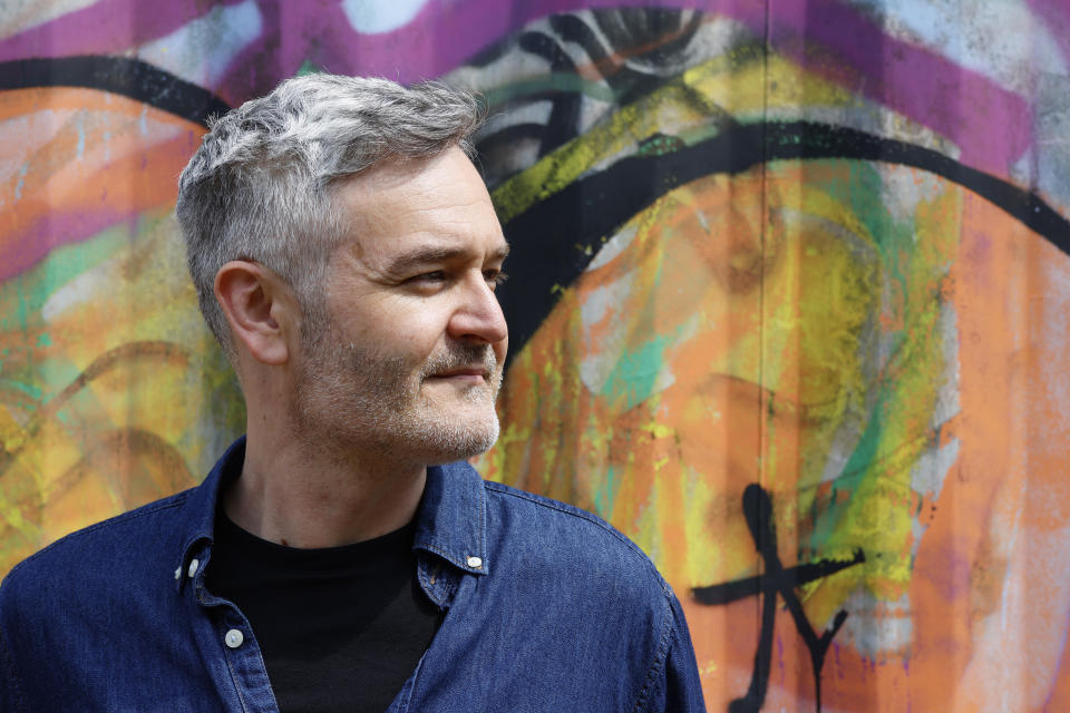 A man looking away in front of a graffitied wall