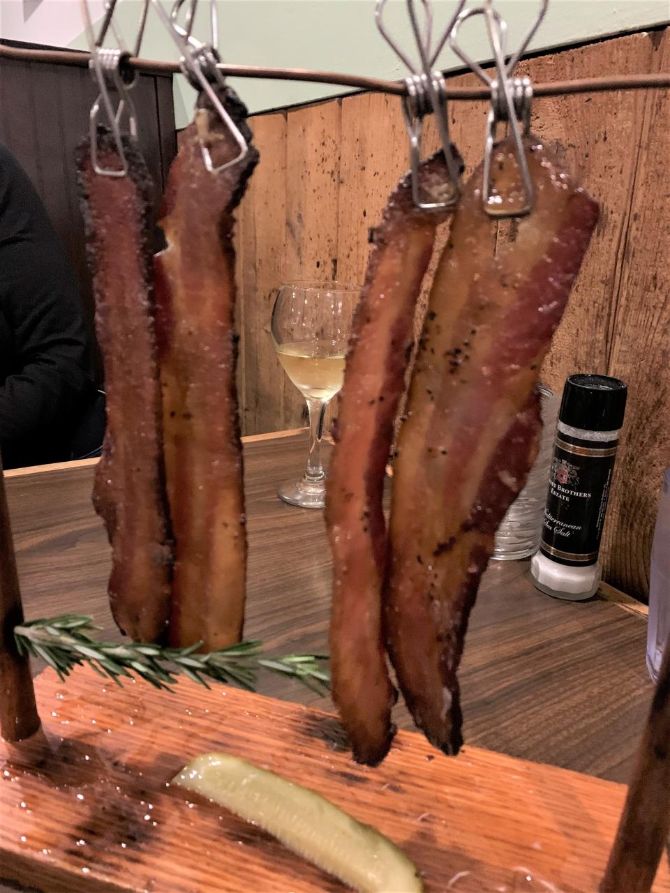The Sweet Swine at 12A Buoy is thick-cut black pepper and maple glazed bacon strips dangling from a clothesline by metal clips.