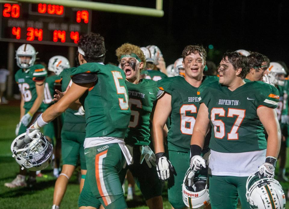 Hopkinton High School football players celebrate after the game, defeating Wayland, 20-19, in the season opener for both teams, Sept. 8, 2023. From left: senior Sam Pantera; senior Logan Richardson; senior Mike Scardino; and senior Jason Piccioli.