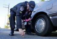 88-year-old Ed Robles, a member of the Retired Senior Volunteer Patrol, marks a car's position on the road while answering a parking complaint in San Diego, California, United States March 10, 2015. (REUTERS/Mike Blake)