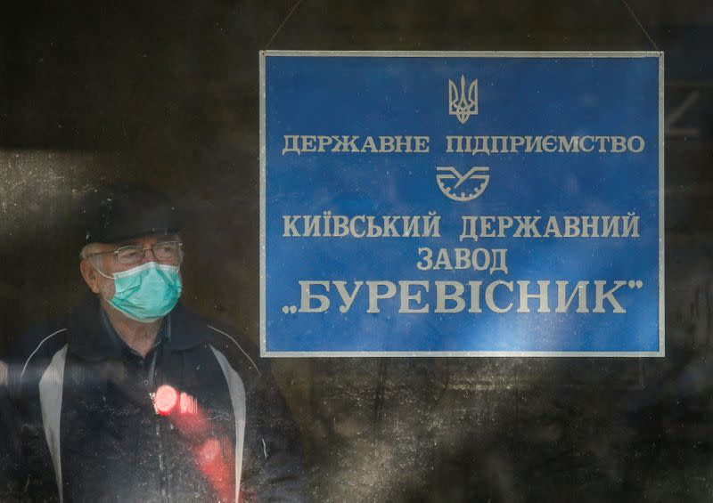 A watchman wearing a protective mask stands at an entrance of the state-run Burevisnyk factory in Kiev