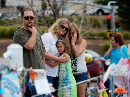 Una familia de Aurora (Colorado) se emociona ante el altar en memoria de las víctimas del tiroteo del estreno de Batman.