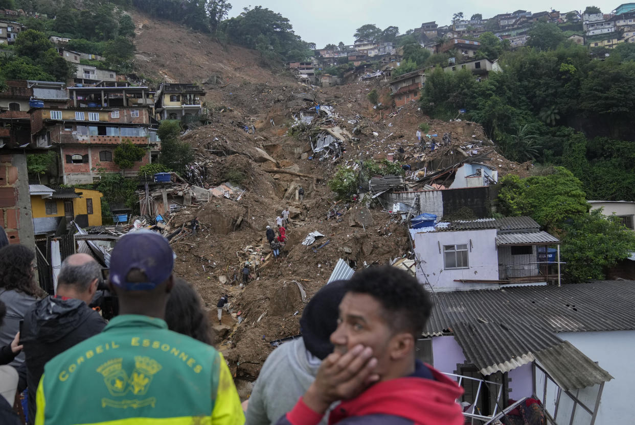 Rescue workers and residents look for victims in an area affected by landslides in Petropolis, Brazil, Wednesday, Feb. 16, 2022. Heavy rains set off mudslides and floods in a mountainous region of Rio de Janeiro state, killing multiple people, authorities reported. (AP Photo/Silvia Izquierdo)