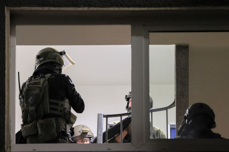 Special police forces stand in the hallway of an apartment building. A man describing himself as a Reich citizen "Reichsbuerger" threatened police officers in Velbert with a knife, triggering a SWAT operation. Christoph Reichwein/dpa