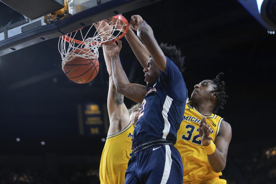 Virginia guard Reece Beekman (2) dunks on Michigan center Hunter Dickinson and Tarris Reed Jr. (32) in the first half of an NCAA college basketball game in Ann Arbor, Mich., Tuesday, Nov. 29, 2022. (AP Photo/Paul Sancya)