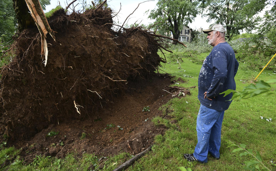 Tim Hinkle stands near the root ball of a downed tree on his property on King Road near Riegle Road on Wednesday, June 10, 2020. Strong storms with heavy winds swept across Jackson County, Mich., causing power outages, downing trees and damaging property. Hinkle had about a dozen trees either completely toppled or with limbs sent flying. His home also sustained damage. (J. Scott Park/Jackson Citizen Patriot via AP)