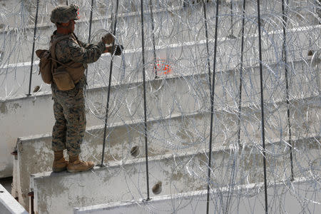 A U.S. Marine helps to make a concertina wire barricade at the U.S. Mexico border in preparation for the arrival of a caravan of migrants at the San Ysidro border crossing in San Diego, California, U.S., November 13, 2018. REUTERS/Mike Blake