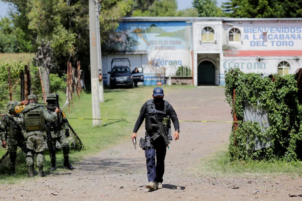 A police officer and soldiers keep watch outside a bar after a massacre in a bar left eleven people dead: REUTERS