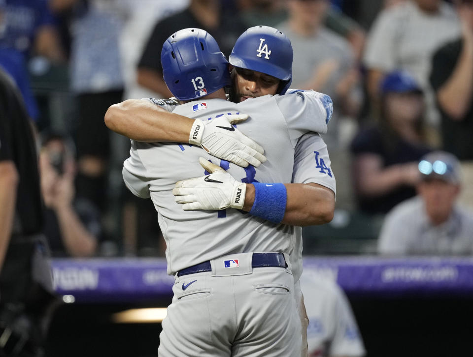 Los Angeles Dodgers' Max Muncy, front, is hugged by Albert Pujols after Muncy hit a solo home run off Colorado Rockies relief pitcher Carlos Estevez during the eighth inning of a baseball game Saturday, July 17, 2021, in Denver. (AP Photo/David Zalubowski)