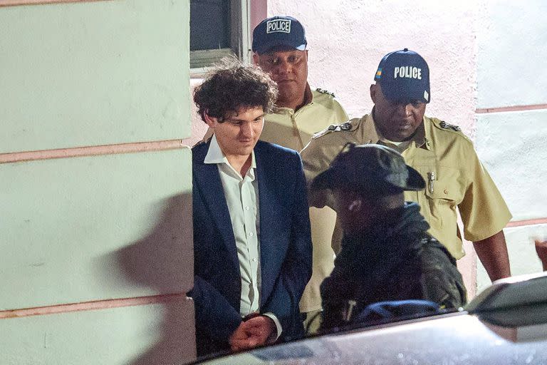 TOPSHOT - FTX founder Sam Bankman-Fried (L) is led away handcuffed by officers of the Royal Bahamas Police Force in Nassau, Bahamas on December 13, 2022. - Disgraced cryptocurrency tycoon Sam Bankman-Fried was hit with multiple criminal charges December 13, 2022, accused of committing one of the biggest financial frauds in US history. Bankman-Fried will serve time at The Bahamas Department of Corrections until February 8, 2023. (Photo by Mario Duncanson / AFP)