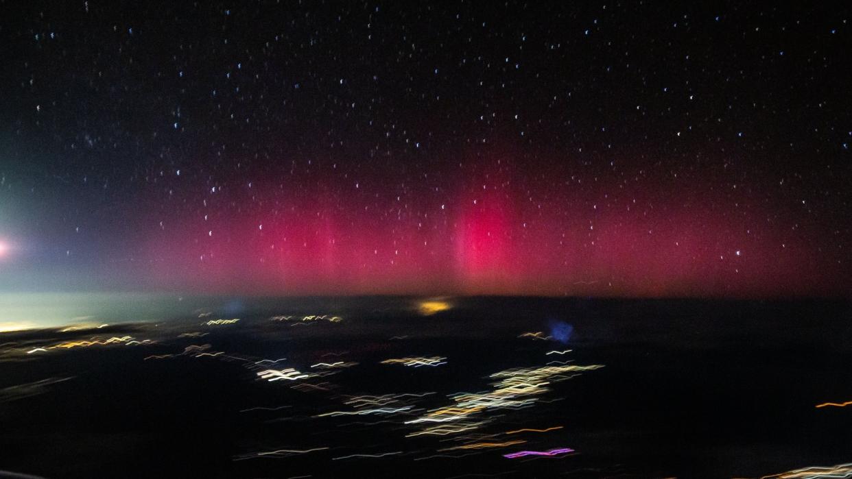  A purple aurora glows on the horizon in a picture taken from an airplane mid flight 