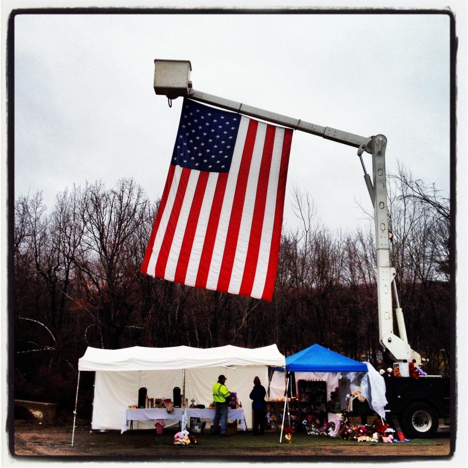 A giant American flag is displayed above a tent in an overflow parking lot in Newtown, Conn.