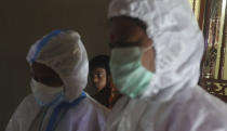 A boy looks on as health workers screen people for COVID-19 symptoms at a residential building in Dharavi, one of Asia's biggest slums, in Mumbai, India, Friday, Aug. 7, 2020. As India hit another grim milestone in the coronavirus pandemic on Friday, crossing 2 million cases and more than 41,000 deaths, community health volunteers went on strike complaining they were ill-equipped to respond to the wave of infection in rural areas. (AP Photo/Rafiq Maqbool)