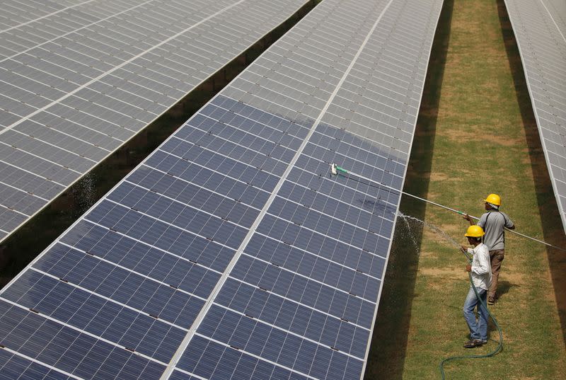 FILE PHOTO: Workers clean photovoltaic panels inside a solar power plant in Gujarat