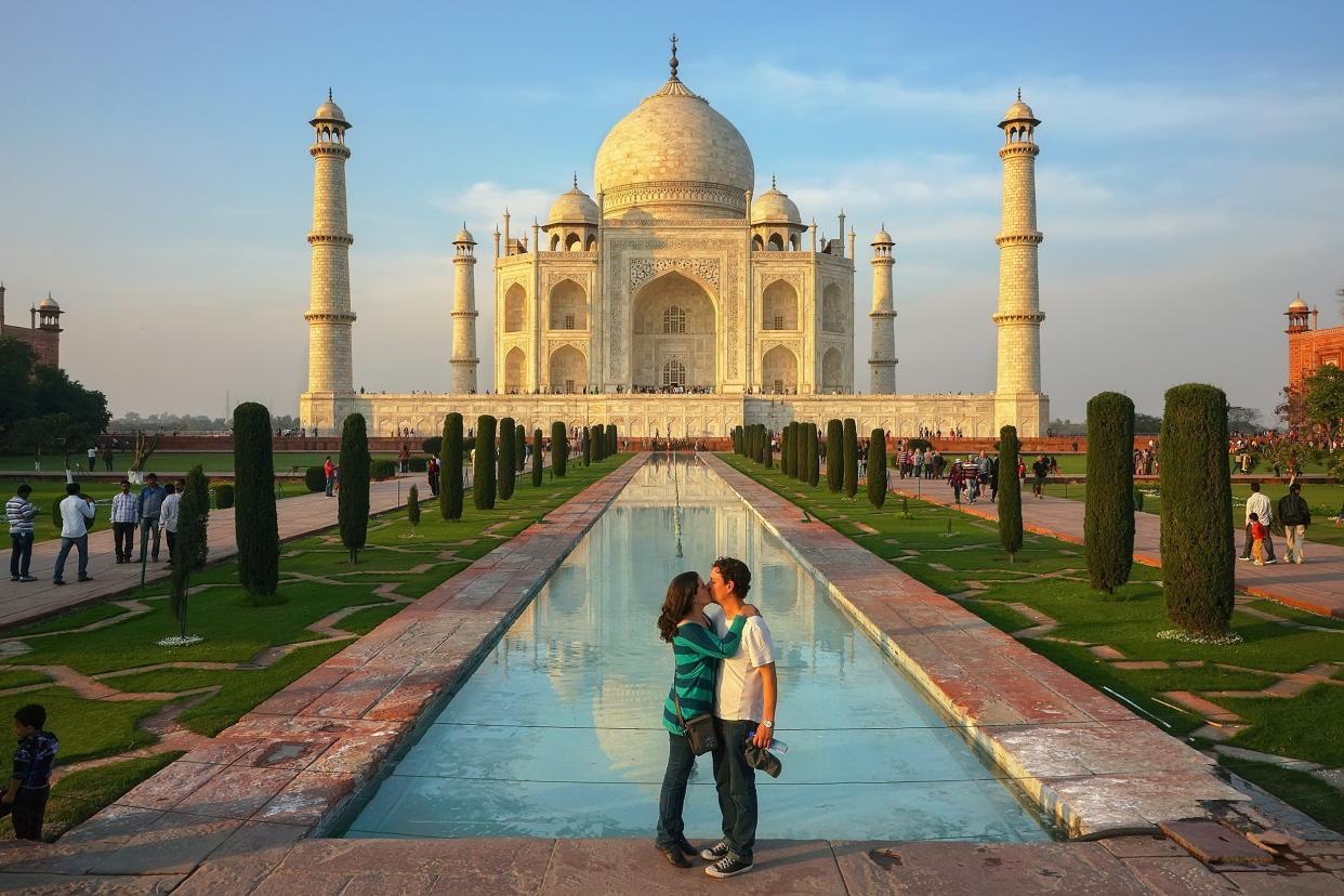 European man and young woman kiss in front of Taj Mahal