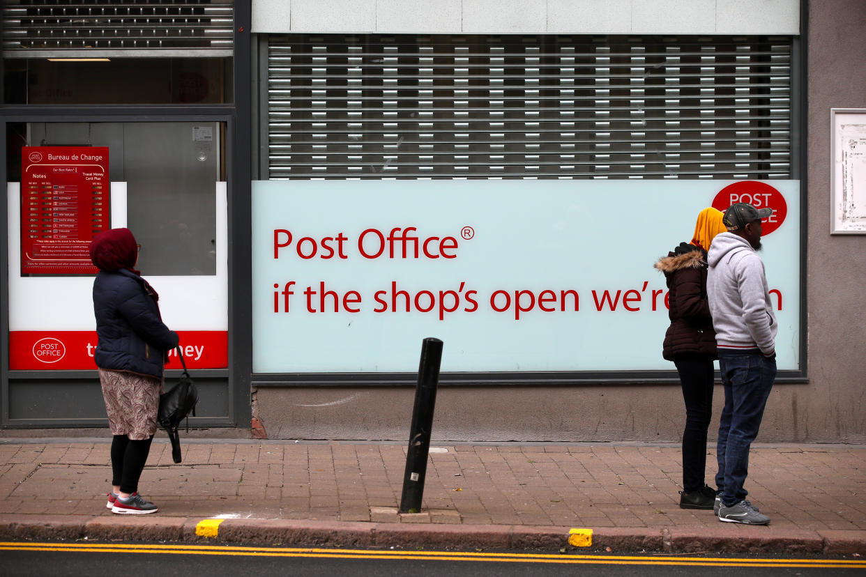 People maintain social distancing as they queue outside a post office in Wolverhampton city centre as the UK continues in lockdown to help curb the spread of the coronavirus.