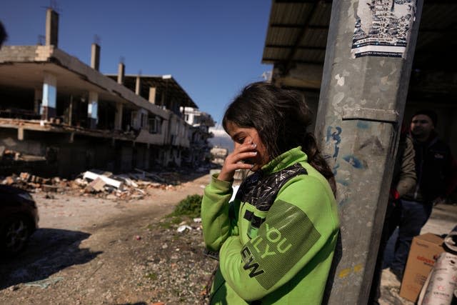 A girl stands next to destroyed buildings in Antakya, southern Turkey, Wednesday, Feb. 8, 2023