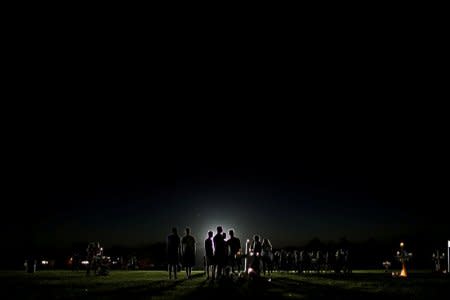 People mourn next to crosses placed in a park to commemorate the victims of the shooting at Marjory Stoneman Douglas High School, in Parkland, Florida, U.S., February 16, 2018. REUTERS/Carlos Garcia Rawlins